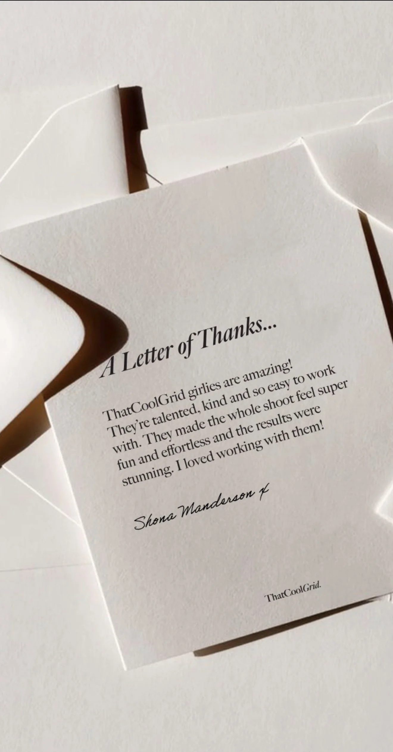 Close-up of a handwritten thank you note, client testimonial with decorative paper and a partial view of a white envelope.