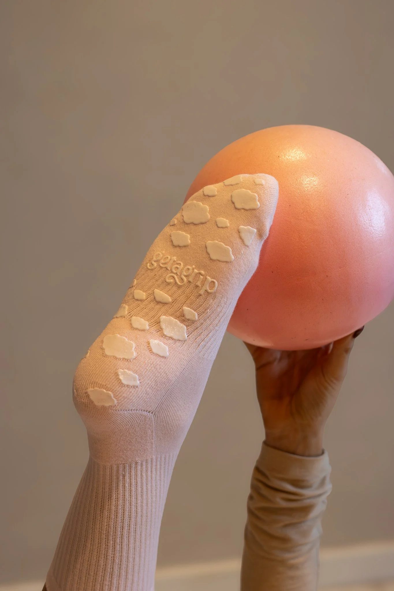 Close-up of a person holding an egg in one hand, wearing a beige sock with white cloud patterns. Shona Manderson, Get A Grip.