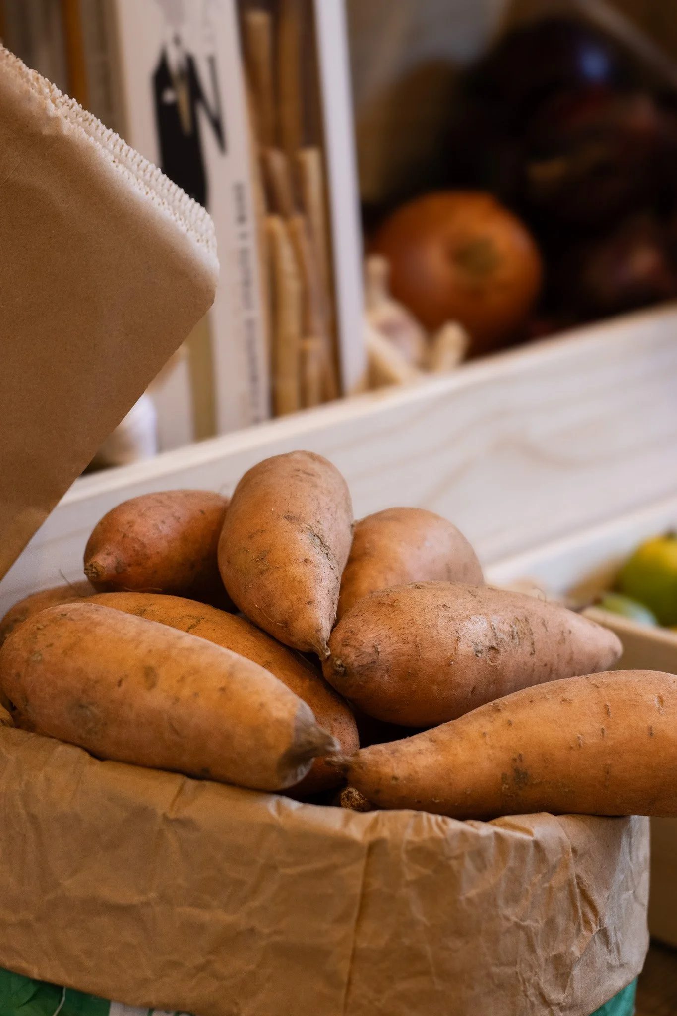 A paper bag filled with sweet potatoes. The Cotswold Farm.